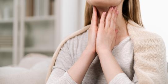 Frau fasst sich an den Hals