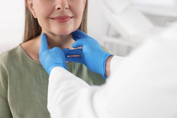 Arzt tastet Hals der Patientin ab